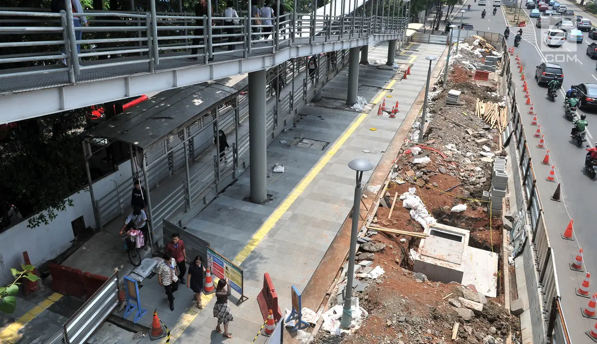 Pejalan kaki melintas di jembatan penyeberangan dekat proyek penataan ulang trotoar Jalan Jenderal Sudirman, Jakarta, Kamis (25/10). Pejalan kaki harus memutar ketika turun dari jembatan penyeberangan melalui jalur khusus. (Merdeka.com/Iqbal Nugroho)