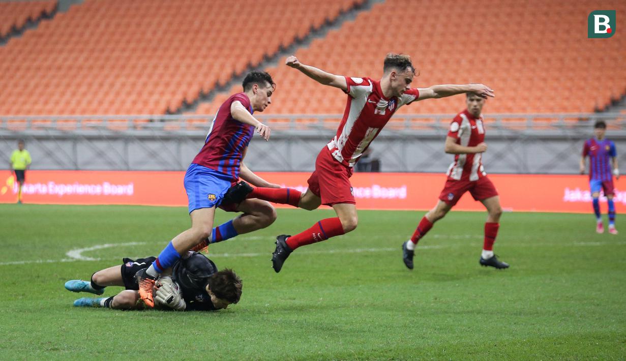 Kiper Atletico Madrid U-18, Luciano Riveros Garcia (kiri) berusaha menyelamatkan bola saat laga International Youth Championship 2021 antara Barcelona U-18 melawan Atletico Madrid U-18 di Jakarta International Stadium, Jakarta, Jumat (15/04/2022). (Bola.com/Bagaskara Lazuardi)