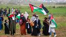 Para wanita mengibarkan bendera Palestina selama bentrokan dengan tentara Israel dalam demonstrasi untuk memperingati Hari Tanah di Tepi Barat, Sabtu (30/3). (Photo by ANAS BABA/AFP)