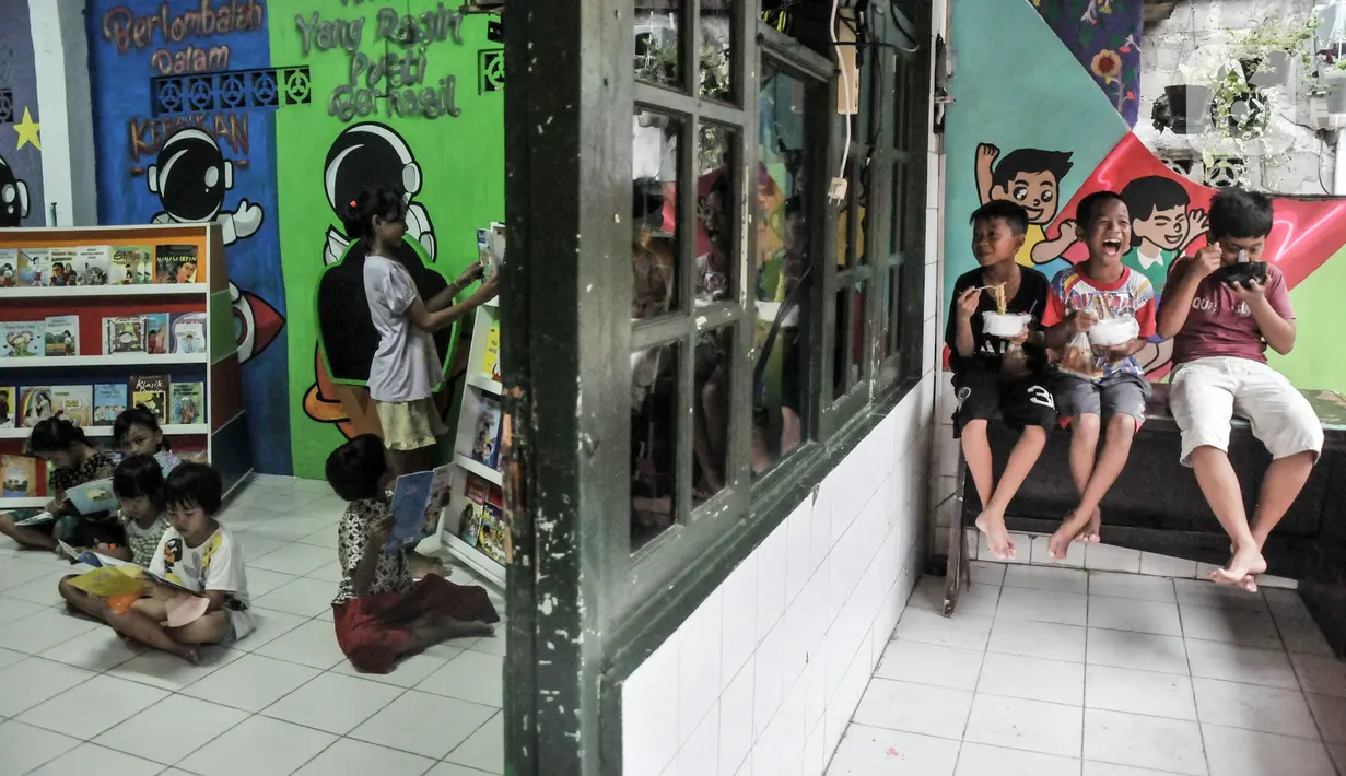 Anak-anak membaca buku (kiri) sementara yang lainnya makan (kanan) di Pojok Baca Kampung Literasi RW 09, Kampung Pondok Jati, Palmeriam, Jakarta Timur, Senin (10/10/2022). Pemerintah Provinsi DKI Jakarta berkolaborasi dengan Kelurahan Palmeriam dan Komunitas Bale Buku Jakarta membangun Pojok Baca Palmeriam. (merdeka.com/Iqbal S. Nugroho)