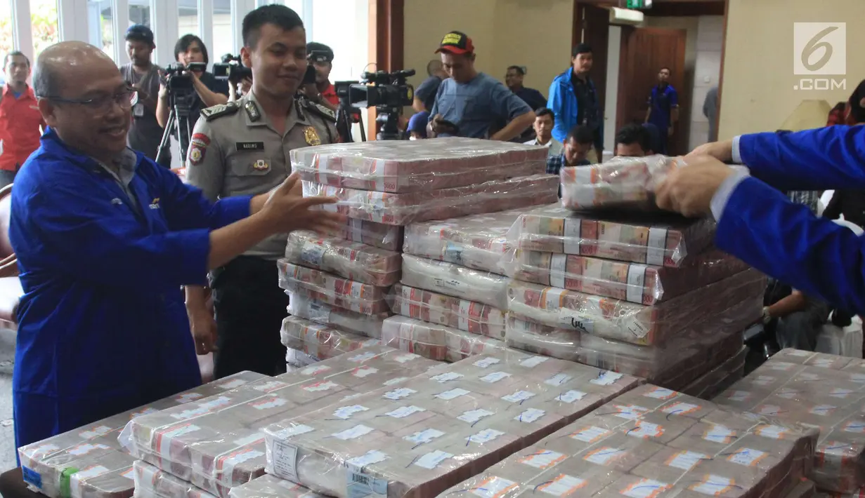 Pegawai menata uang ganti rugi korupsi BLBI dengan terpidana Samadikun Hartono di Gedung Bank Mandiri, Jakarta, Kamis (17/5). Samadikun membayar tunai sisa uang pengganti sesuai dengan vonis yang diterimanya senilai Rp 87. (Liputan6.com/Angga Yuniar)