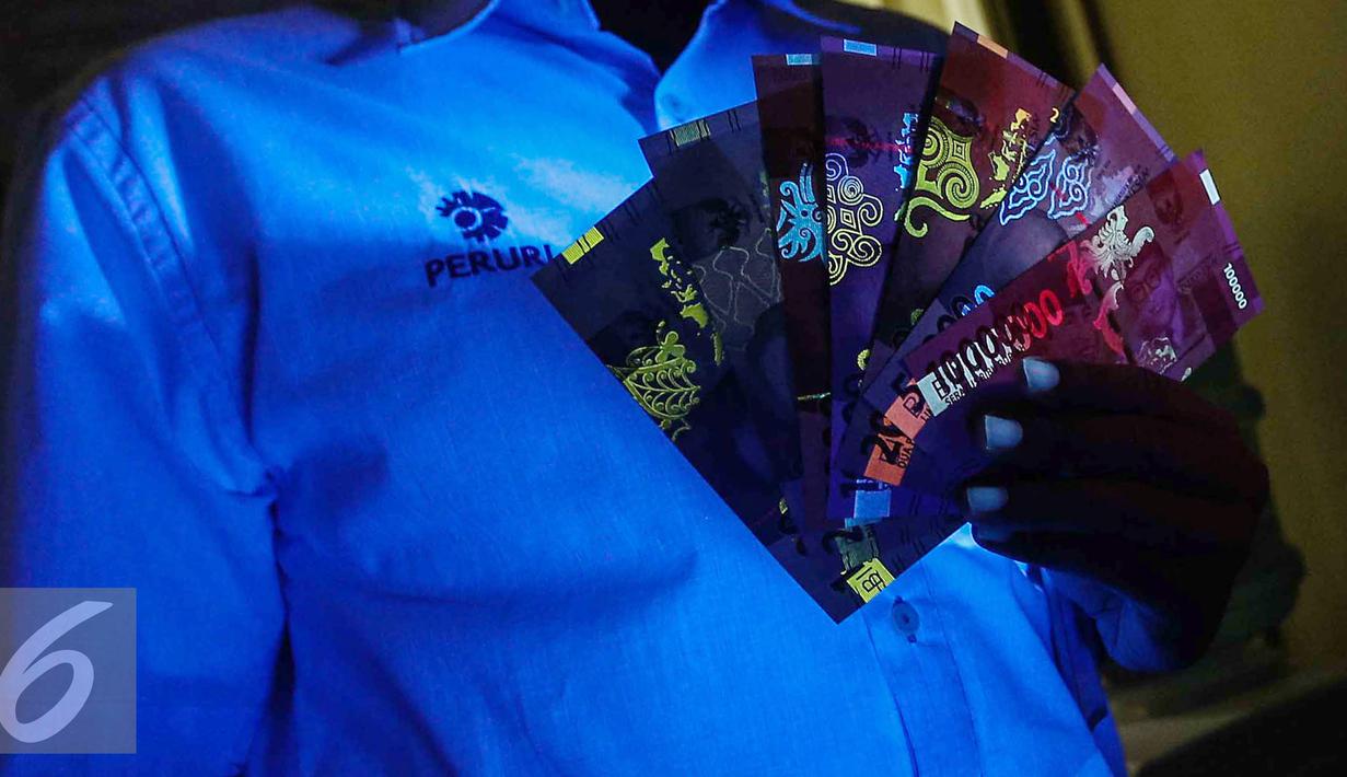 Petugas menunjukan uang kertas rupiah yang disinari lampu ultraviolet saat peruri media visit di Perusahaan Umum Percetakan Uang Indonesia (Peruri), Karawang, Jawa Barat, Rabu (18/1). (Liputan6.com/Faizal Fanani)