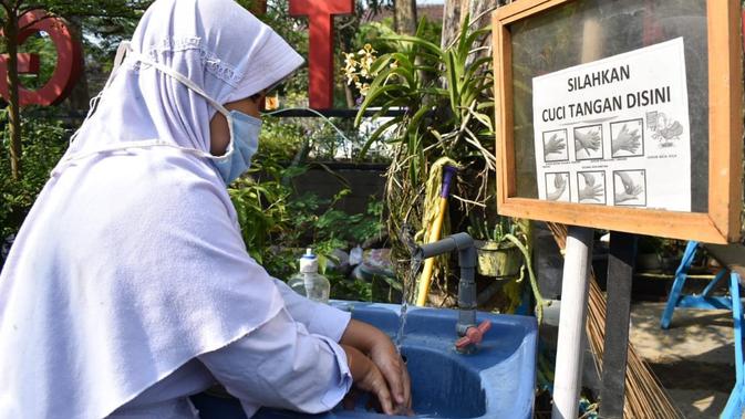 Seorang siswa sedang mencuci tangan dalam penerapan protokol kesehatan. Sebagian siswa di Jalan Turangga Timur, memanfaatkan akses internet dalam rangka belajar jarak jauh di rumah warga. Akses internet gratis ini diinisiasi oleh warga. (Liputan6.com/Huyogo Simbolon)