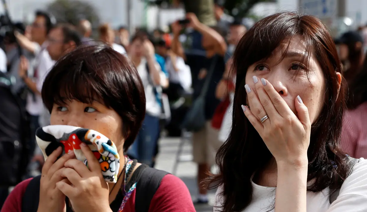 Ekspresi dua warga saat menyaksikan video pidato Kaisar Akihito di Tokyo, Jepang, (8/8). Kaisar yang bertahta sejak 25 tahun lalu mengungkapkan kekhawatiran tidak mampu melaksanakan tugas-tugas Kekaisaran secara penuh. (REUTERS/Kim Kyung-Hoon)