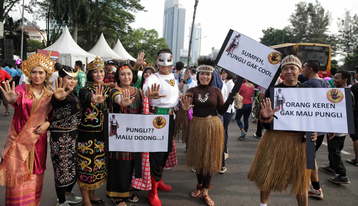 Satgas saber pungli mengenakan kostum super hero dan tradisional berfoto bersama saat mensosialisasikan tolak pungli di Car Free Day, Jakarta, Minggu (12/11). (Liputan6.com/Faizal Fanani)