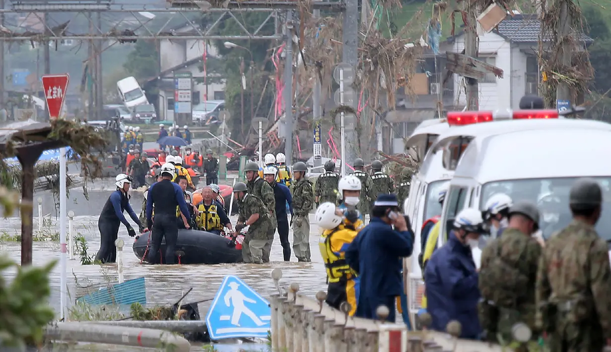 Warga dievakuasi dari daerah yang terkena banjir menggunakan perahu karet di Kuma village, prefektur Kumamoto, Jepang, Minggu (5/7/2020). Banjir di wilayah Kumamoto yang memicu tanah longsor ini telah menghancurkan ratusan rumah dan kendaraan serta membuat jembatan terputus. (STR/JIJI PRESS/AFP)