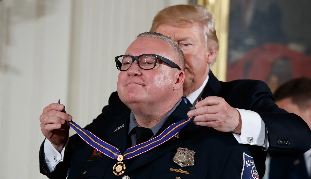 Presiden Donald Trump memberikan Medali Kehormatan kepada Kevin Jobe dari Departemen Kepolisian Alexandria, Va di Gedung Putih, Washington, (27/7). Pelaku diidentifikasi bernama James T. Hodgkinson dari Belleville, Illinois 66 tahun. (AP Photo/Evan Vucci)