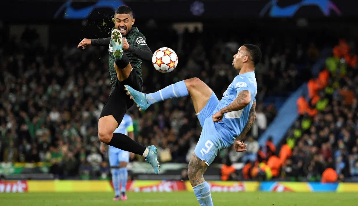 Penyerang Sporting Lisbon, Bruno Tabata (kiri) bersaing dengan penyerang Manchester City Gabriel Jesus pada leg kedua babak 16 besar Liga Champions, Kamis (10/3/2022) dini hari WIB. Manchester City tetap melaju ke perempat final meski bermain imbang 0-0 dengan Sporting Lisbon. (Oli SCARFF/AFP)