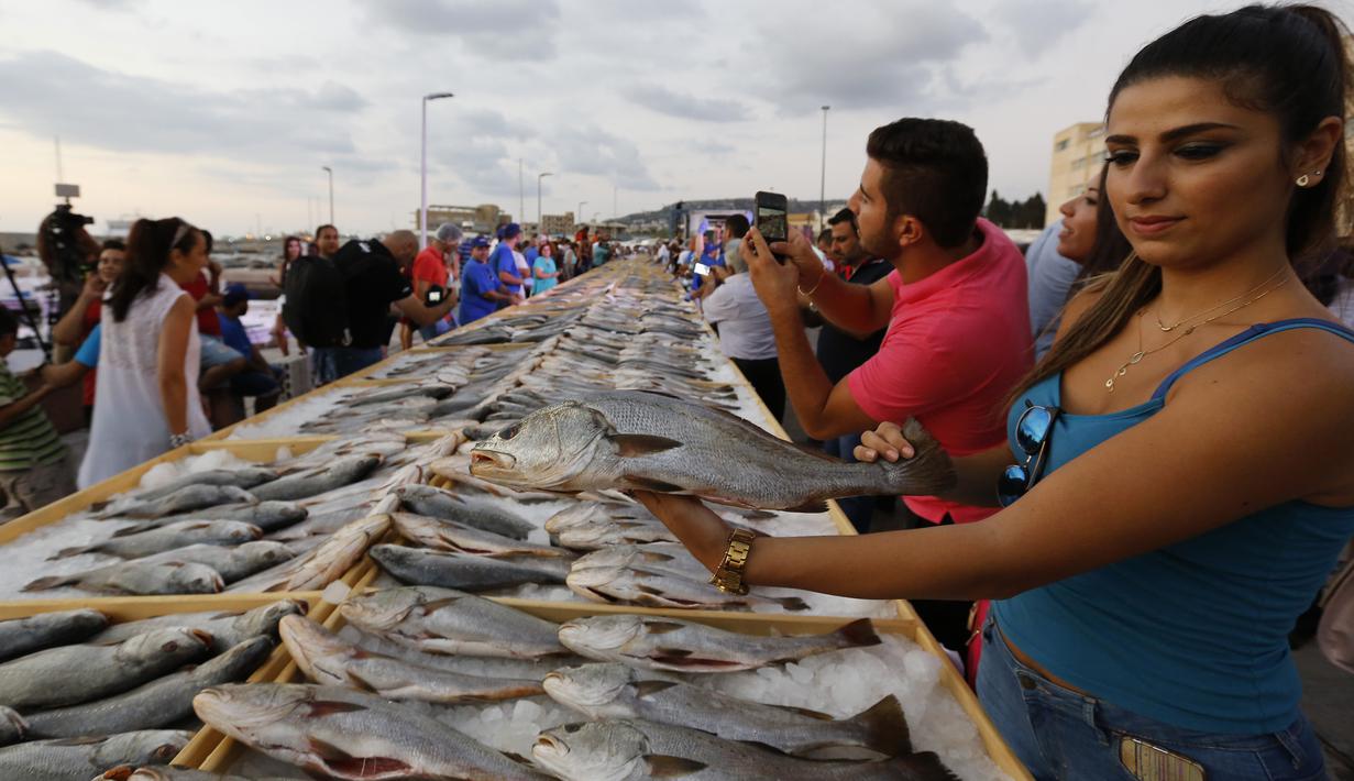 Seorang anggota Lebanon's Batroun Traders Association memegang ikan yang berhasil memecahkan rekor makanan laut terbanyak di daerah kota pantai Batroun, Minggu (4/9). Menurut panitia, total ikan yang dikumpul sebanyak 2 ton 614 kg. (AFP PHOTO/Anwar AMRO)