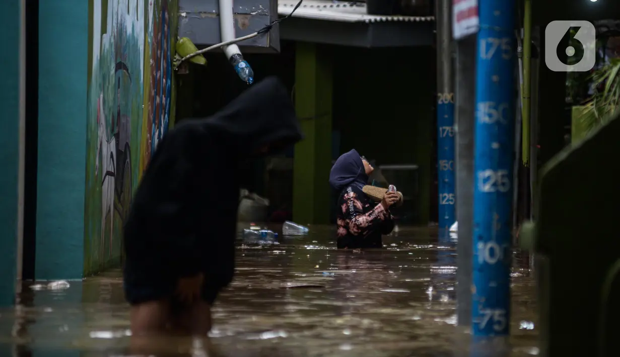 Warga melintasi banjir di kawasan Kebon Pala, Kampung Melayu, Jakarta Timur, Sabtu (16/7/2022). Karena rumahnya terendam banjir, sejumlah warga sudah mulai menyelamatkan barang-barang berharga ke tempat yang lebih tinggi. (merdeka.com/Imam Buhori)