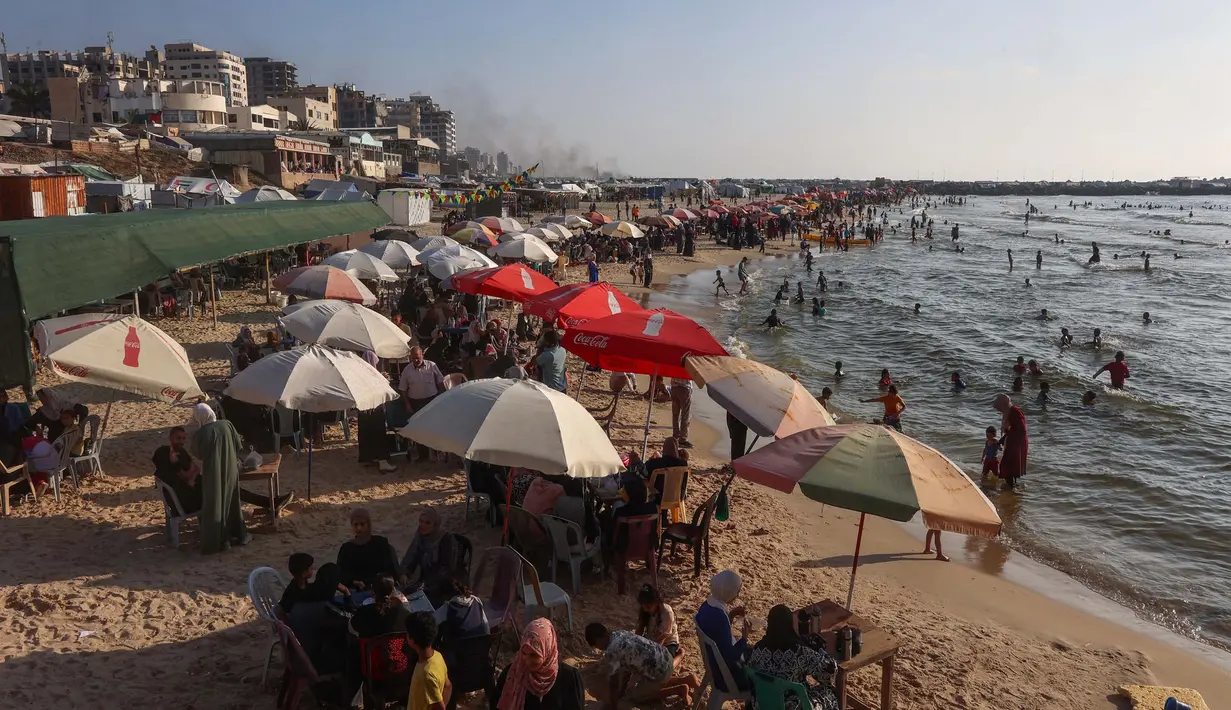 Untuk menghindari cuaca panas, warga Palestina yang mengungsi meninggalkan tenda pengungsian dan berkumpul di salah satu pantai di kota Gaza. (Omar AL-QATTAA/AFP)