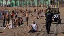 Petugas polisi meminta orang-orang untuk tidak duduk sambil berpatroli di pantai di Barcelona, Spanyol, Rabu, (20/5/2020). Barcelona mengizinkan orang untuk berjalan di pantai untuk pertama kalinya sejak dimulainya penguncian virus coronavirus lebih dari dua bulan lalu. (AP Photo/Emilio Morenatti)