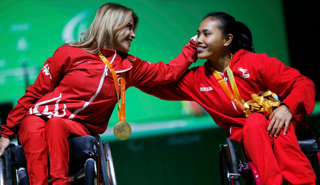 Atlet Indonesia, Ni Nengah Widiasih memeluk peraih emas asal Turki, Nazmiye Muratli di podium juara cabang angkat berat Paralimpiade 2016 Rio de Janeiro, Kamis (8/9). Ni Nengah mempersembahkan medali pertama untuk Indonesia. (REUTERS/Ueslei Marcelino)