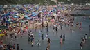Para pengunjung bermain dan bersantai di bawah sinar matahari di Pantai Bournemouth, Selatan Inggris pada Selasa 26 Mei 2026, saat kondisi gelombang panas menyebar ke sebagian wilayah tenggara Inggris dan London. (JUSTIN TALLIS/AFP)