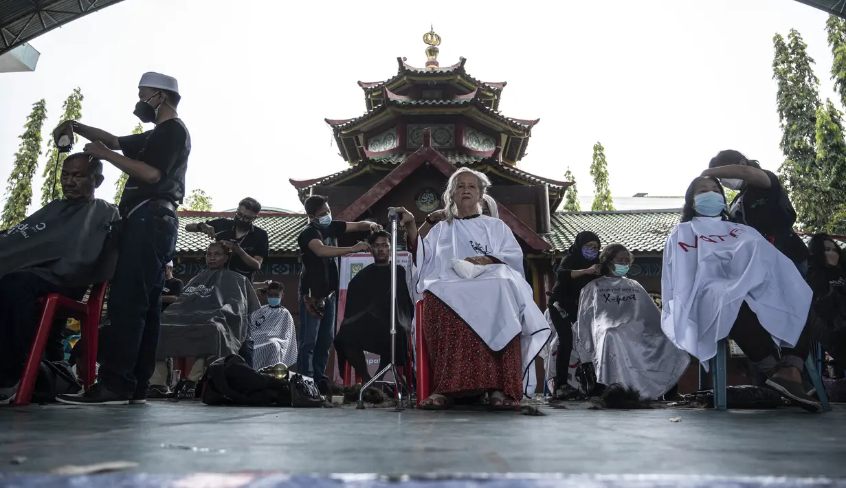 Penata rambut memberikan potongan rambut gratis sebagai bagian dari amal Muslim untuk yang membutuhkan saat umat Islam di seluruh dunia merayakan bulan suci Ramadhan di Muhammad Cheng Hoo di Surabaya (18/4/2022). (AFP/Juni Kriswanto)