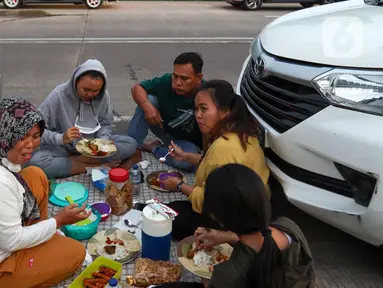 Sejumlah pemudik berbuka puasa Ramadhan sambil beristirahat di KM 102 ruas Tol Cikopo-Palimanan, Subang, Jawa Barat, Kamis (28/4/2022). Padatnya sejumlah rest area di sepanjang jalan tol Trans Jawa membuat pemudik memanfaatkan bahu jalan untuk berbuka puasa dan istirahat sejenak. (Liputan6.com/Herman Zakharia)
