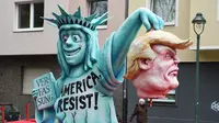 Sebuah patung berbentuk menyerupai Patung Liberty dan Presiden AS ikut dalam karnaval tradisional 'Rose Monday' di Dusseldorf, Jerman Barat, Senin (27/2). Karnaval 'Rose Monday' berisi sindiran satir para pemimpin dunia. (AFP PHOTO / Patrik STOLLARZ)