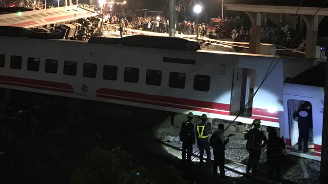 Petugas penyelamat berkumpul di lokasi tergelincirnya kereta Puyuma Express di Yilan, Taiwan, Minggu (21/10). Kantor Berita Pusat Taiwan melaporkan bahwa lusinan orang mungkin masih terperangkap di dalam gerbong kereta. (AP Photo/Johnson Lai)
