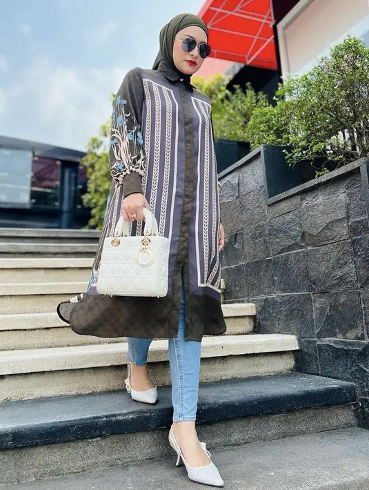 Potret berikutnya ia tampil mengenakan tunik lengan pajang bermotif didominasi warna hijau yang serasi dengan kerudungnya. Atasan dipadu celana denim serta handbag Lady Dior putih serasi dengan stiletto heelsnya. Credit: Instagram (@nathalieholscher)