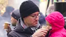 Pengunjung memberi minum anak perempuannya saat Riga Street Food Festival di Riga, Latvia, Sabtu (18/1/2020). Api unggun dan kios-kios makanan didirikan di sudut Jalan Kalku dan Valnu di Kota Tua Riga agar orang-orang dapat menikmati berbagai hidangan populer dari kota tersebut. (Xinhua/Janis)