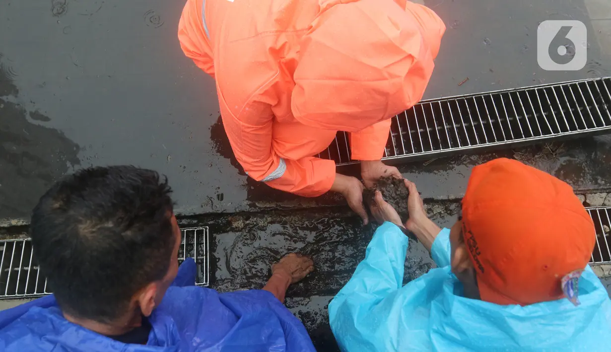 Petugas Penanganan Prasarana dan Sarana Umum (PPSU) membersihkan saluran air di kawasan Gelora Bung Karno, Jakarta, Selasa (17/12/2019). Petugas PPSU membersikan saluran air saat terjadi genangan usai hujan deras mengguyur Jakarta. (Liputan6.com/Herman Zakharia)
