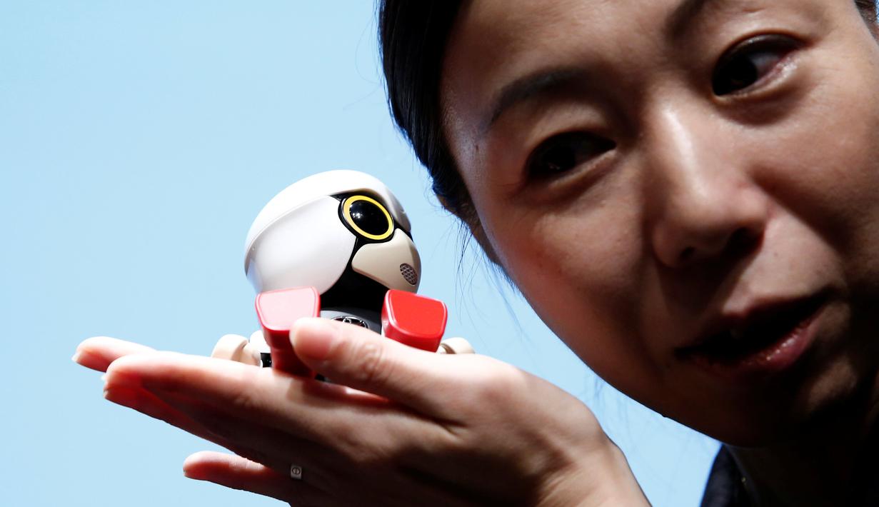 Seorang wanita memegang Robot Mini Kirobo saat diperkenalkan di Tokyo, Jepang pada 27 September 2016. Toyota masih menggembangkan keterampilan Kirobo Mini agar memiliki lebih banyak kemampuan. (REUTERS/Kim Kyung-Hoon)