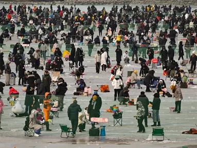 Orang-orang memancing melalui lubang-lubang di sungai yang membeku selama festival tahunan memancing di atas es, Hwacheon, Korea Selatan, pada Sabtu 10 Januari 2026. Ribuan orang memadati area Festival Tahunan Memancing di Atas Es Hwacheon tahun 2026. (Shin Yong-ju/AFP)