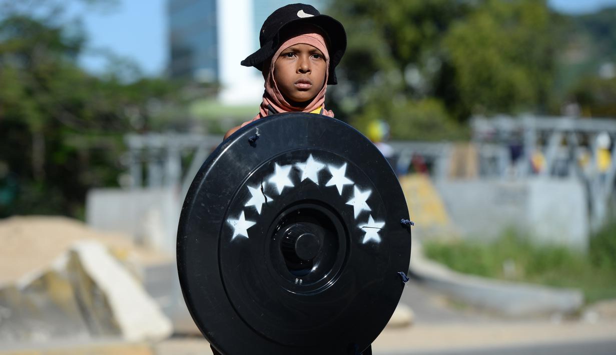 Seorang anak laki-laki membawa tameng berwarna hitam saat mengambil bagian dalam demonstrasi untuk menentang pemerintahan Presiden Nicolas Maduro, di Caracas (4/7). (AP Photo / Federico Parra)