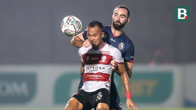 Madura United kembali dapat peluang lewat Sansan Fauzi (depan) di menit 23. Sansan yang mendapatkan kawalan ketat dari Sergio Domingos Reis Silva berhasil menendang bola ke gawang dan ditangkap kiper Arema FC. (Bola.com/Bagaskara Lazuardi)