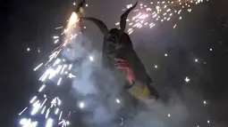 Seorang warga berpakaian seperti hantu dengan memegang tongkat kembang api selama perayaan " Correfocs ", Mallorca, Spanyol, (24/1). Ini merupakan perayaan tradisional yang menandai menandai akhir dari perayaan lokal di Palma. (REUTERS / Enrique Calvo)
