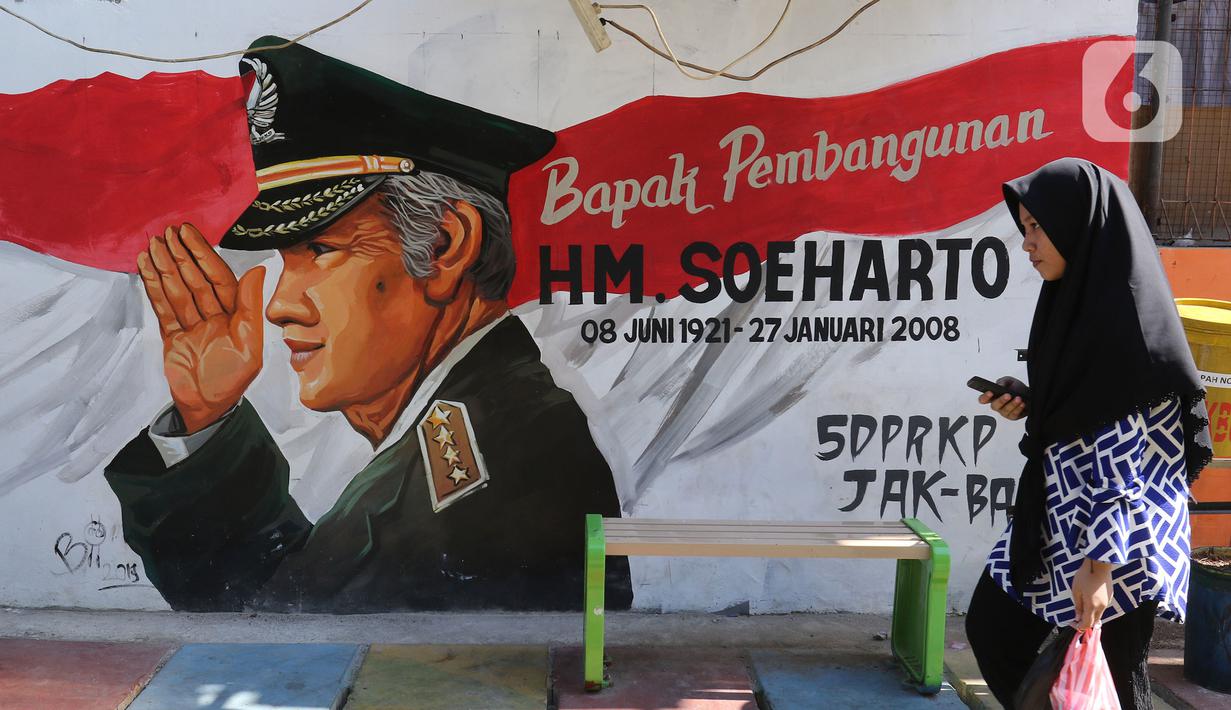 Seorang warga melintasi mural di Kampung Budaya Kawasan Jakarta Barat, Selasa (19/11/2019). Pemprov Jakarta Barat melakukan penataan kawasan pemukiman di beberapa lokasi, salah satunya di Jalan Katalia I Timur. (Liputan6.com/Herman Zakharia)