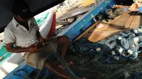 Warga kampung Pasar Ikan Luar Batang sebagian besar berprofesi nelayan. Sembari menanti adzan maghrib, Jufri (50) mereparasi jaring ikannya. (Andrian Martinus Tunay/Liputan6.com)