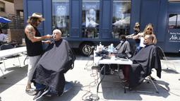 Penata rambut selebriti Jason Schneidman (kiri) dari The Men's Groomer mencukur rambut Samuel Velasquez saat cukur rambut gratis untuk para tunawisma dalam Los Angeles Mission di Los Angeles, California, Amerika Serikat, 12 Juli 2021. (Frederic J. BROWN/AFP)