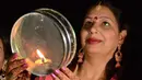 Seorang wanita Hindu yang sudah menikah memanjatkan doa selama festival Karva Chauth di Amritsar,  Kamis (17/10/2019). Karva Chauth merupakan festival di mana wanita-wanita yang sudah menikah di India akan berpuasa dan memohon umur panjang serta keselamatan untuk suami mereka. (NARINDER NANU/AFP)