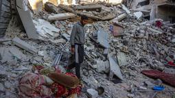 Seorang pria berjalan di tengah reruntuhan rumah yang hancur akibat serangan Israel di Khan Younis, Jalur Gaza selatan, pada Rabu 29 Oktober 2025. Hingga Rabu (29/10/2025), dikabarkan sedikitnya 91 orang tewas akibat serangan itu. (BASHAR TALEB/AFP)