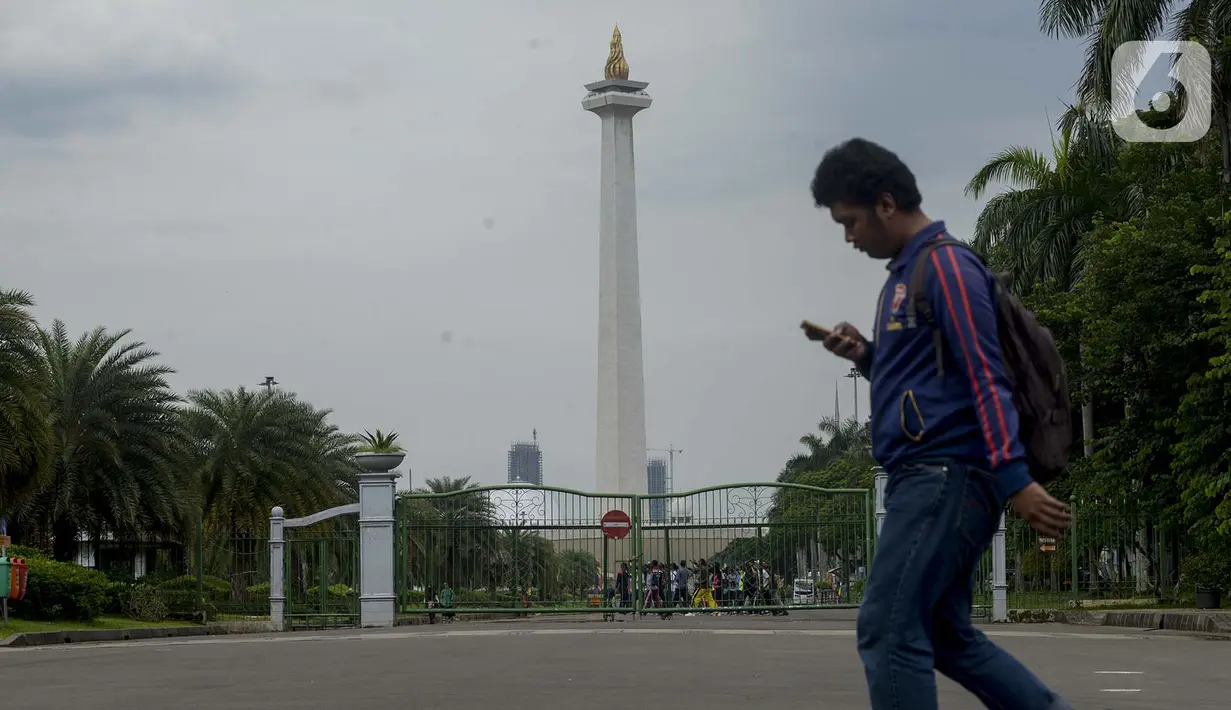 Pejalan kaki berjalan di kawasan Monumen Nasional (Monas) yang akan dijadikan arena lintasan balapan Formula E 2020, Jakarta, Selasa (11/2/2020). Ajang ini dilakukan di kawasan Monas setelah mendapatkan persetujuan dari Komisi Pengarah Kawasan Medan Merdeka. (merdeka.com/Imam Buhori)