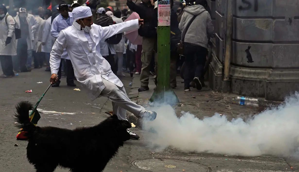 Mahasiswa kedokteran menendang gas air mata saat demonstrasi dekat lapangan Murilo di La Paz, Bolivia (19/12). Para dokter ini juga melakukan mogok makan dari senin kemarin. (AFP Photo/Jorge Bernal)