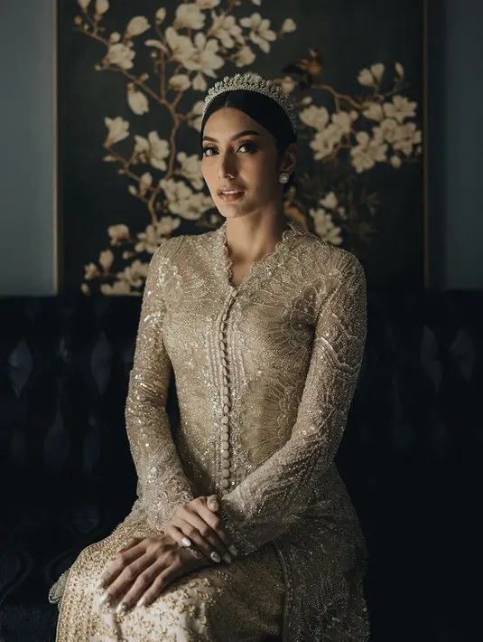 Tyas sendiri tampil elegan saat akad dengan dibalut kebaya panjang dihiasi bordiran dengan detail kancing depan. Dipadukan songket warna keemasan yang serasi dengan songket sang pengantin pria. [@morden.co]