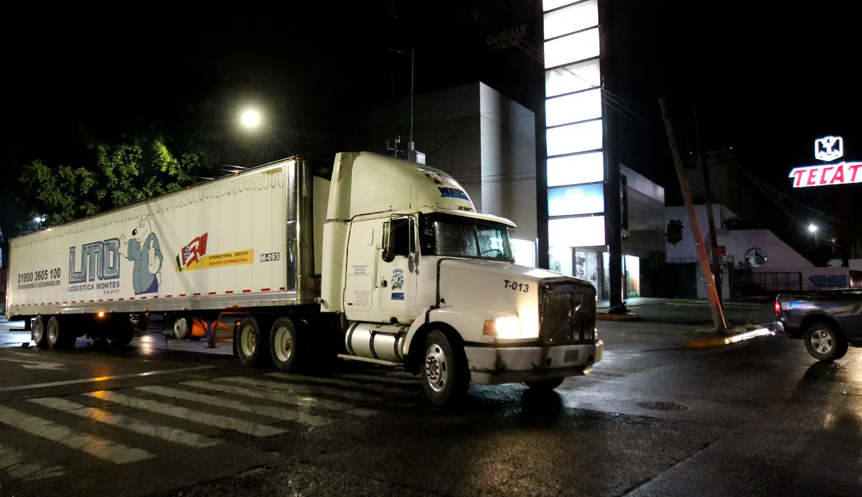 Sebuah kontainer truk trailer berisi lebih dari 100 mayat tak teridentifikasi dipindahkan dari Guadalajara menuju Jalisco di Meksiko, Senin (17/9). Penduduk lokal memprotes aparat di Guadalajara setelah menyium bau busuk yang ditimbulkan (AFP/Ulises Ruiz)