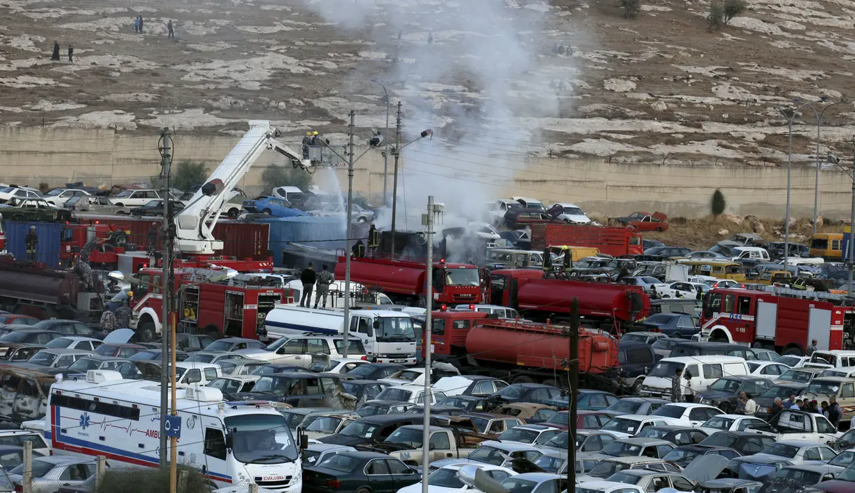 Pemadam kebakaran memadamkan api di lokasi meledaknya dua kontainer yang membawa kembang api di halaman departemen bea cukai di Amman, Yordania, Senin (26/10). Kejadian tersebut menewaskan delapan orang dan 12 lainnya terluka. (REUTERS / Stringer)