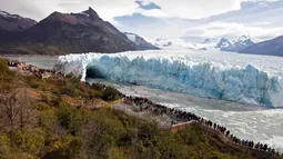 Wisatawan melihat fenomena langka runtuhnya dinding es raksasa dari Gletser Perito Moreno di Taman Nasional Los Glaciares, Argentina, Kamis (10/3). Siklus pecahnya es ini tidak teratur dan berulang secara alami di setiap frekuensi. (AFP PHOTO/Walter Diaz)