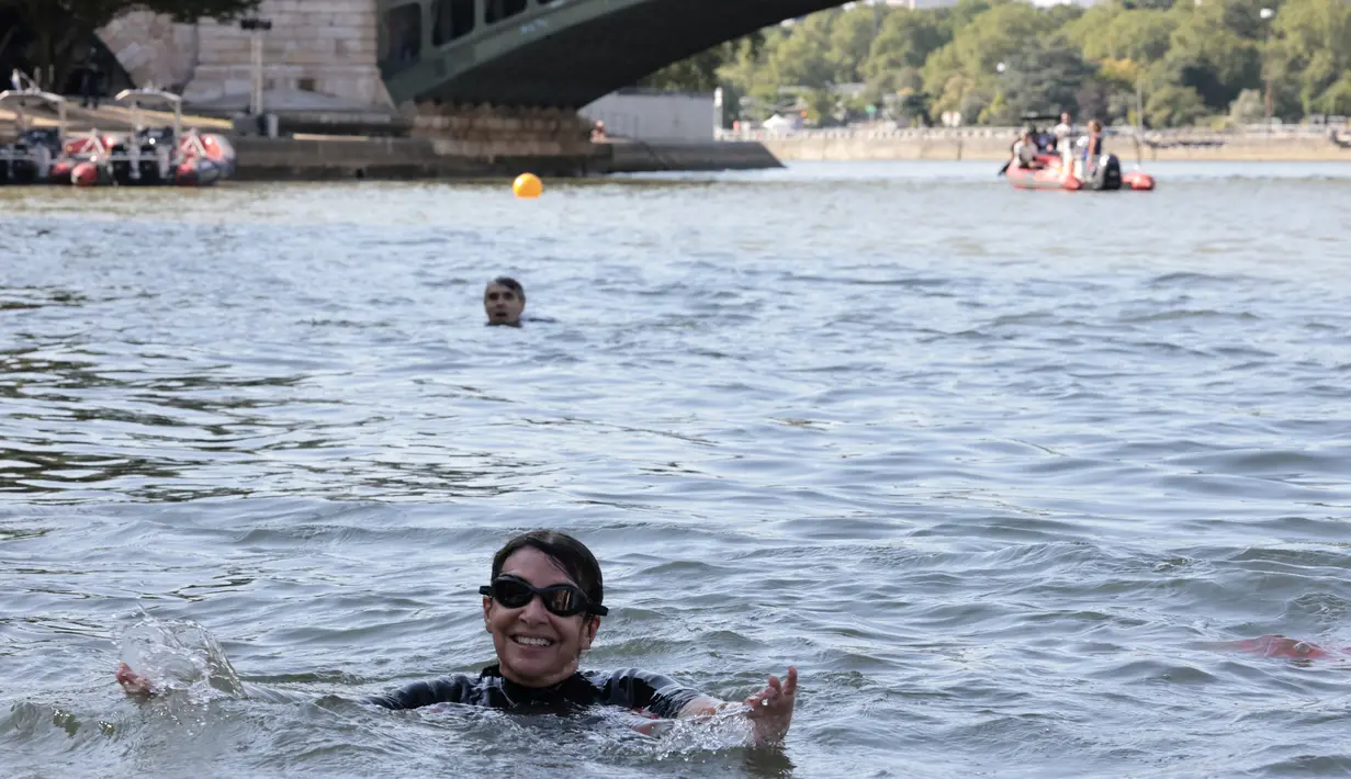 Mengenakan wetsuit dan kacamata renang, Hidalgo terjun ke sungai dekat Balai Kota yang megah dan Katedral Notre Dame. (JOEL SAGET / POOL / AFP)