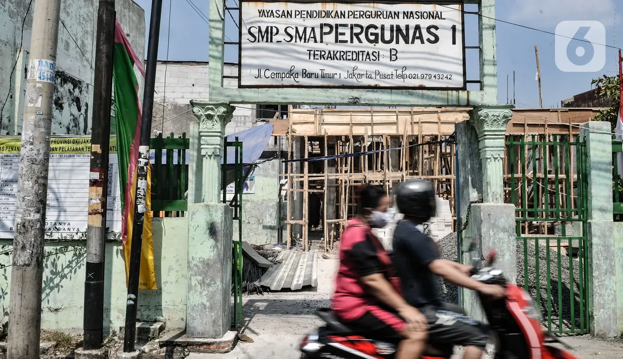 Pengendara sepeda motor saat melintasi pembangunan gedung di yayasan Pergunas I di Jalan Cempaka Baru I, RT 015/003, Kemayoran, Jakarta, Senin (31/8/2020). Pembangunan itu menutup akses jalur keluar masuk rumah warga dan memaksanya harus melewati pintu samping. (merdeka.com/Iqbal S Nugroho)