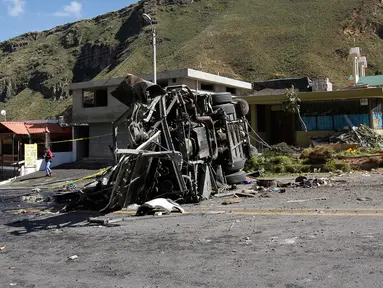 Petugas polisi melihat sebuah kendaraan yang bertabrakan dengan bus pembawa turis asal Kolombia dan Venezuela di Pifo, Ekuador, Selasa (14/8). Sebanyak 24 orang tewas dan 19 lainnya luka-luka. (AP Photo/Carlos Noriega)