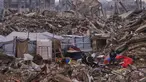 Warga Palestina berdiri di samping tenda yang didirikan di atas reruntuhan bangunan yang hancur akibat serangan udara dan darat Israel di lingkungan Sheikh Radwan, Kota Gaza, Selasa, 30 Desember 2025. Setelah lebih dari dua tahun agresi militer Israel yang menghancurkan wilayah tersebut, kini cuaca dingin ekstrem dan hujan lebat menjadi tantangan besar bagi pengungsi di Jalur Gaza. (AP Photo/Abdel Kareem Hana)