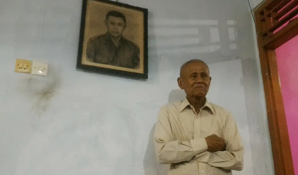 Mantan Anggota Cakrabirawa, Ishak, berfoto dengan latar belakang lukisan saat masih aktif berdinas. Ia masih gagah di usianya yang ke 81 tahun. (/Muhamad Ridlo)
