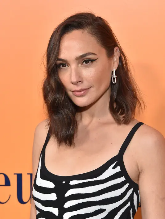 Gal Gadot berpose saat menghadiri Peluncuran Pameran Budaya Veuve Clicquot Solaire di Beverly Hills, California pada 25 Oktober 2022.  Ia menghias pakaiannya dengan sepasang anting-anting. (Lisa O'CONNOR / AFP)