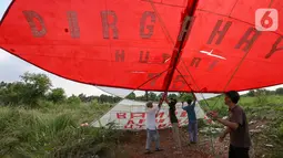 Warga menahan layang-layang merah putih raksasa sebelum diterbangkan di kawasan Bambu Apus, Tangerang Selatan, Senin (17/8/2020). Layangan berukuran 10 X 9 meter yang diterbangkan oleh puluhan warga digelar dalam rangka memperingati HUT Ke-75 RI. (Liputan6.com/Fery Pradolo)