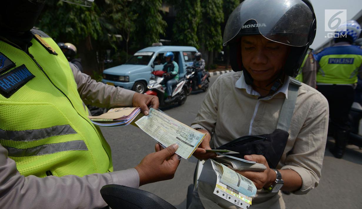 Polisi lalu lintas memeriksa kelengkapan surat pengendara saat razia Operasi Patuh Jaya 2019 di kawasan Kebon Nanas, Jakarta, Kamis (29/8/2019). Operasi ini diharapkan dapat meningkatkan kepatuhan dan ketertiban dalam berlalu lintas serta mengurangi angka kecelakaan. (merdeka.com/Imam Buhori)