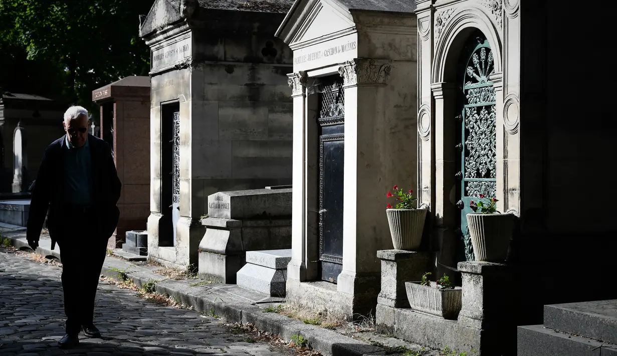 Seorang pria berjalan melewati kuburan di pemakaman Pere Lachaise di Paris (22/7/2019). Pemakaman ini paling banyak didatangi wisatawan di dunia. Artis dan banyak tokoh terkenal dimakamkan di sini. (AFP Photo/Philippe Lopez)